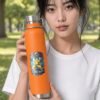 B Like Water Copper Bottle in orange held by model in the park